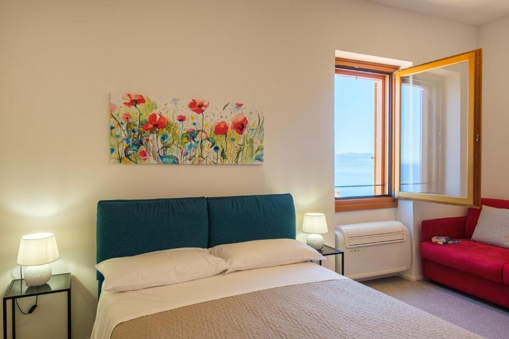 a bedroom with a bed and a red couch at Studio apartment in the Castle Castelsardo in Castelsardo