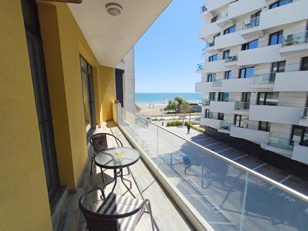 a balcony with a table and chairs and a view of the beach at Apartament RAMI Mamaia Nord in Mamaia Sat/Năvodari
