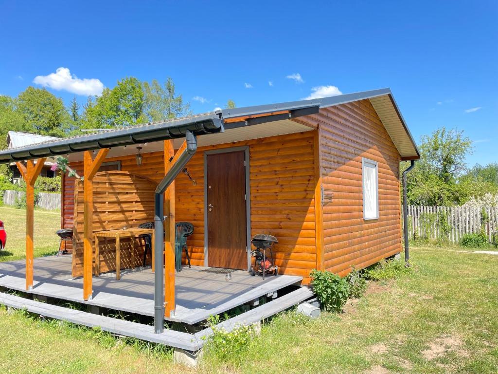 uma cabana de madeira com um alpendre e um deque em Domek letniskowy typu bliźniak em Supraśl