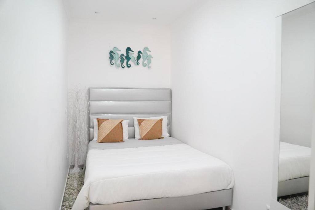 Dormitorio blanco con cama con almohadas de color naranja en Dina Beach house, en Nazaré