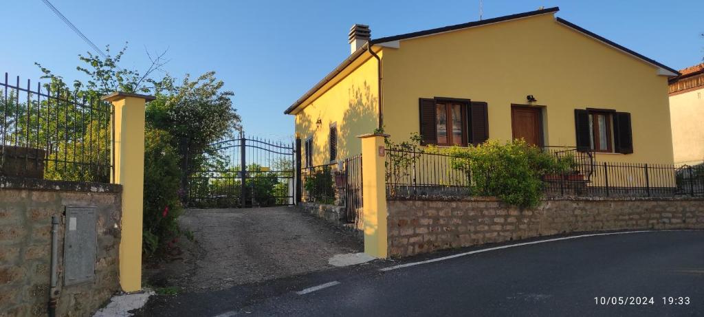 a yellow house with a fence and a street at La casa sul poggio in Lubriano