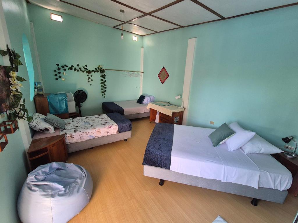 a bedroom with two beds and a table with a chair at Cozy Hosting Galapagos in Puerto Ayora