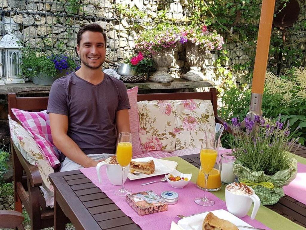 a man sitting at a table with food and orange juice at Appealing apartment in Wilhelmsthal in Wilhelmsthal
