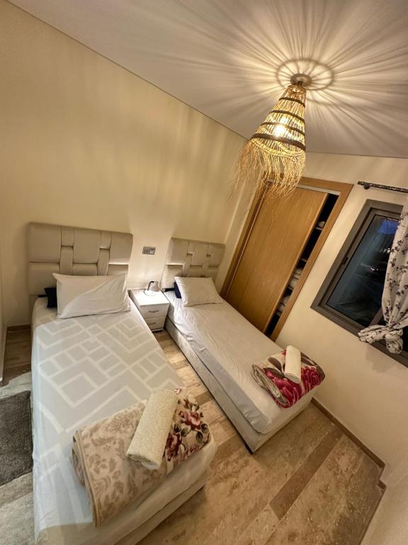 um quarto com 2 camas e um lustre em CHIC & COZY appartement très calme em Casablanca