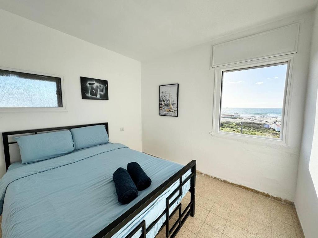 um quarto com uma cama com lençóis azuis e uma janela em Amazing sea view em Qiryat Yam