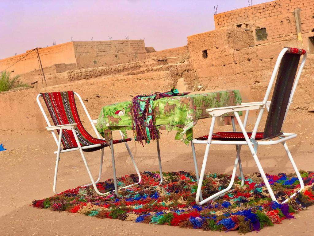 duas cadeiras sentadas ao lado de uma mesa no deserto em Dar Laassri Tours em M'hamid