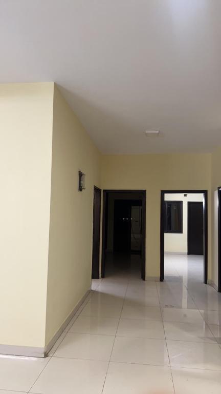 Habitación vacía con paredes blancas y suelo de baldosa blanca. en Saima Jinnah avenue apartments, en Karachi
