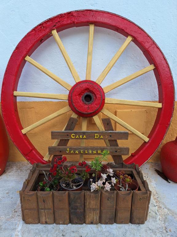 uma roda de vagão de madeira com plantas num vaso de plantas em Casa das Janelinhas - Cottage near Sintra, Mafra, Ericeira em Mafra