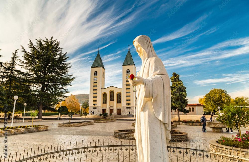 a statue of a nun in front of a church at B&B Family OSTOJIĆ in Međugorje