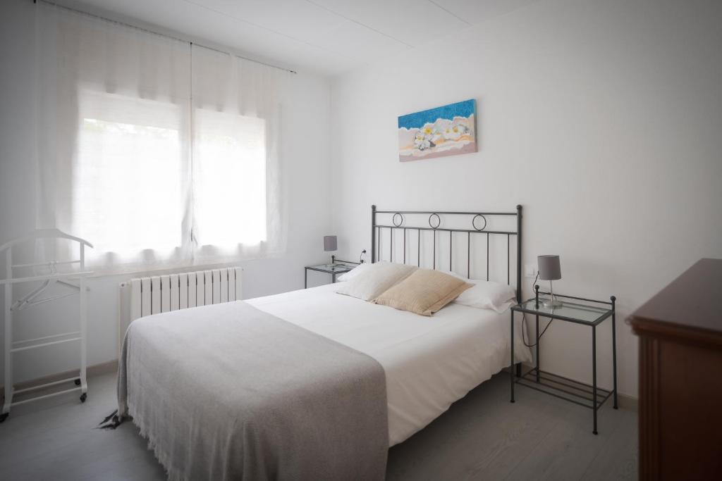 Un dormitorio blanco con una cama grande y una ventana en El Solell de l'àvia, en Olot
