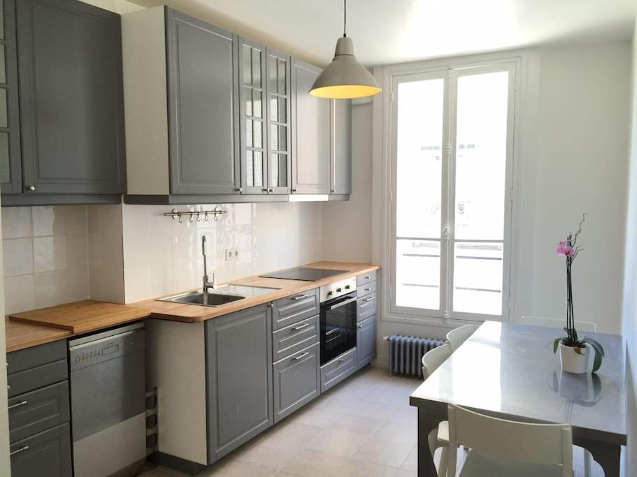 - une cuisine avec des placards gris, un évier et une table dans l'établissement Charmant Appt 2/4 pers Quartier Père Lachaise, à Paris