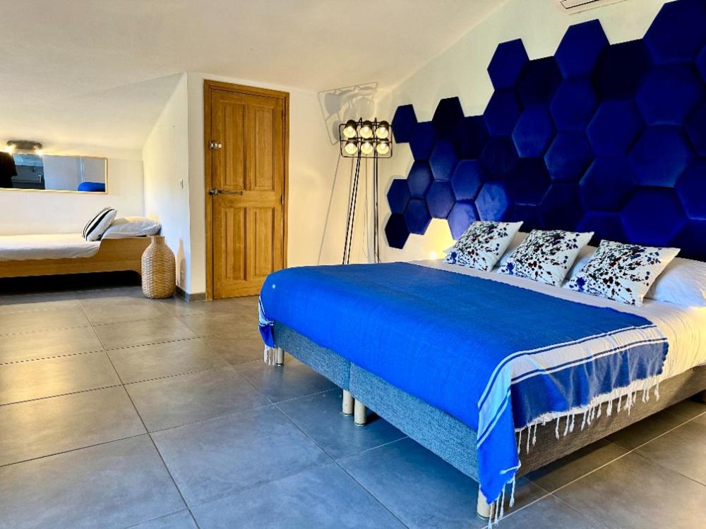une chambre avec un grand lit et une tête de lit bleue dans l'établissement Les Bergeries de Figari, à Figari
