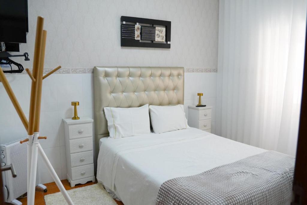 1 dormitorio con 1 cama blanca grande y TV en Dina Beach House Quinzico, en Nazaré