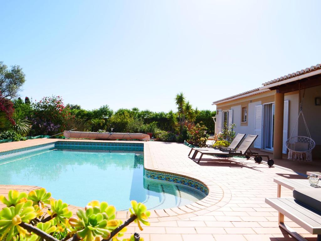 una piscina con 2 sillas y una casa en Villa Rubix, en Luz
