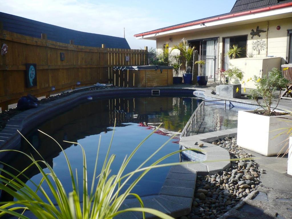 a pool in the yard of a house with blue water at Orana Motor Inn & Restaurant in Kaitaia