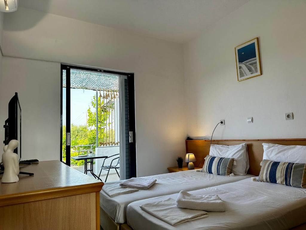 a bedroom with two beds and a desk and a balcony at Elgreco Apartment, at Tigaki, near the sea "4" in Tigaki