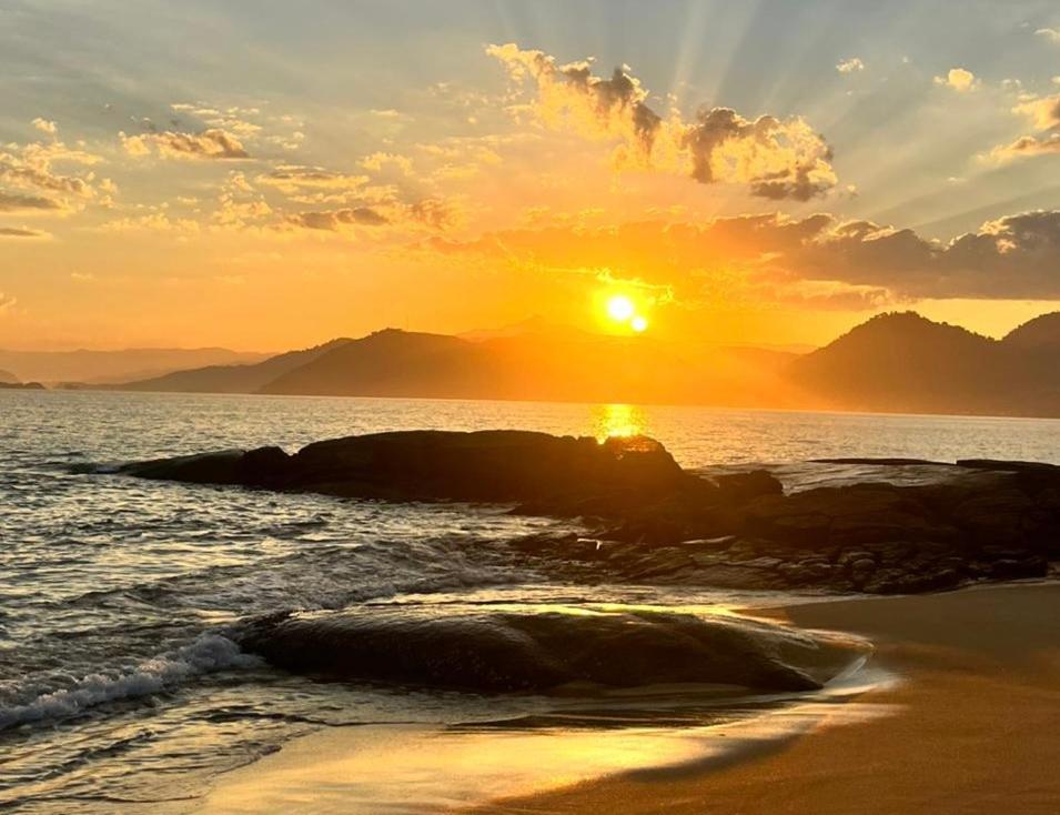 a sunset on the beach with the sun setting at Angra dos Reis - Casa pé na areia na Praia de Fora - Ponta Leste in Angra dos Reis