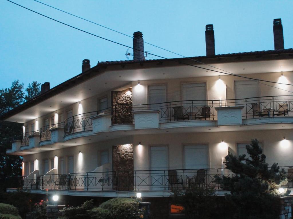 a large white building with balconies and lights at Enastron Hotel in Kato Loutraki
