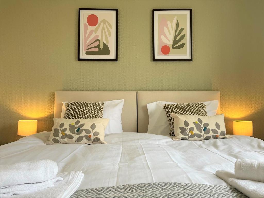a bedroom with a white bed with three pictures on the wall at Ancaster House - Driveway - Great Contractor Base in Lincolnshire