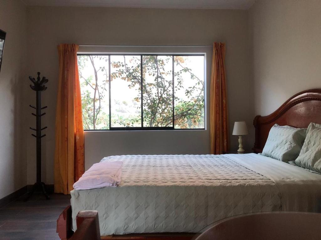 a bedroom with a bed and a large window at Casa Hotel Mamaluna in Lunahuaná