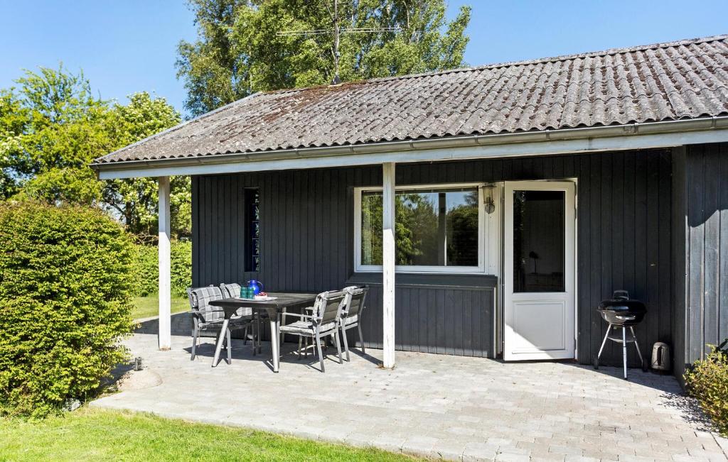 um pátio com uma mesa e cadeiras e uma casa em Amazing Home In Svendborg With Kitchen em Vemmenæs