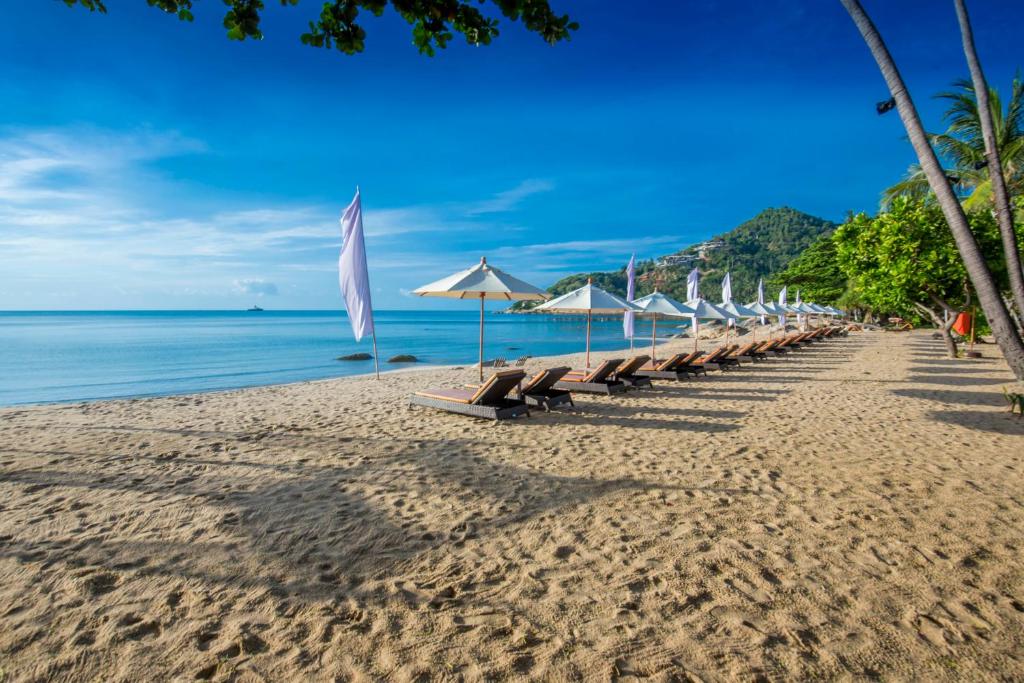 a row of benches on a beach with umbrellas at New Star Beach Resort in Chaweng Noi Beach