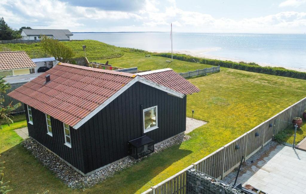 una casa negra con techo rojo junto al océano en Gorgeous Home In Esbjerg V With House Sea View en Esbjerg