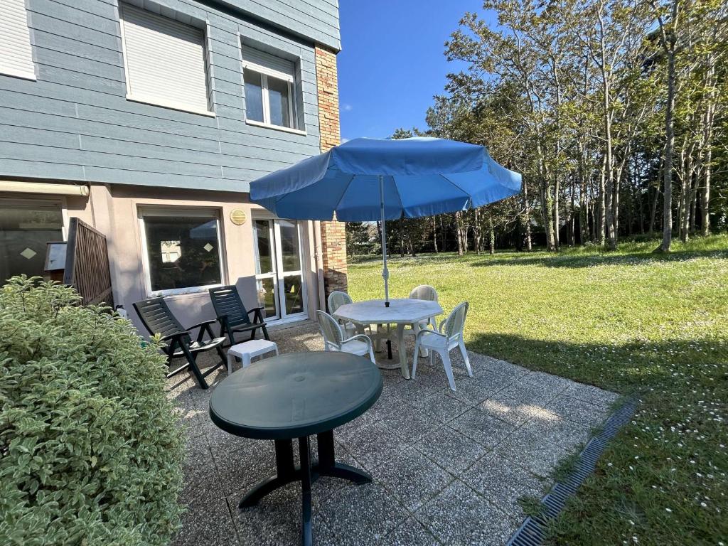 - une table avec un parasol bleu sur la terrasse dans l'établissement Duplex avec terrasse près de la plage et commerces - Saint-Pair-sur-Mer - FR-1-361-374, à Saint-Pair-sur-Mer