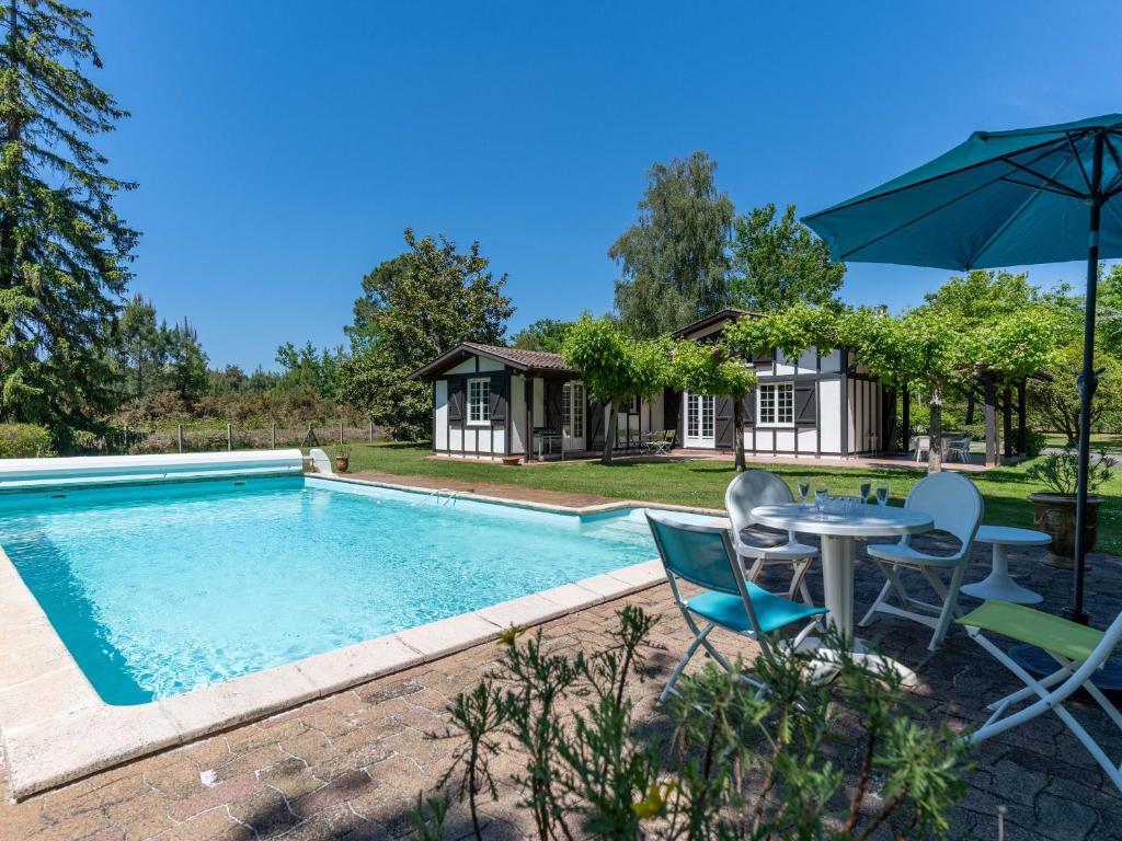 une piscine avec une table, des chaises et un parasol dans l'établissement Maison à Parentis-en-Born: Piscine, 6 pers., Proche Lac et Océan, Pistes Cyclables - FR-1-319-553, à Parentis-en-Born