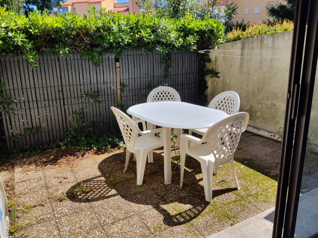 une table blanche et des chaises sur une terrasse dans l'établissement Studio climatisé avec Jardinet, Piscine et Parking à 500m de la Plage - FR-1-776-96, à Argelès-sur-Mer