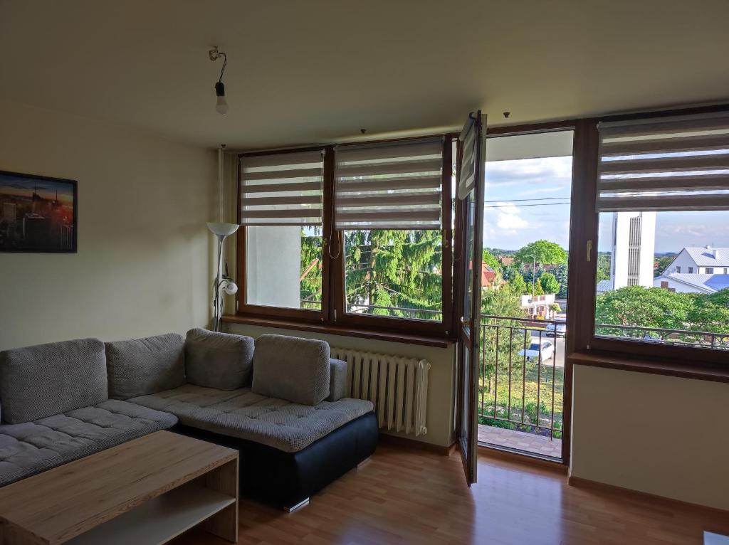 un soggiorno con divano e alcune finestre di Komfortowe mieszkanie a Busko-Zdrój