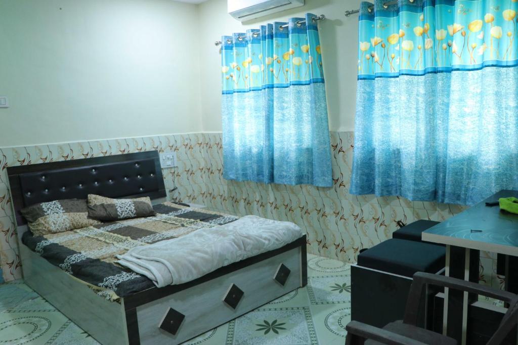 a bedroom with a bed and blue curtains at OYO Galaxy Lodge in Partūr