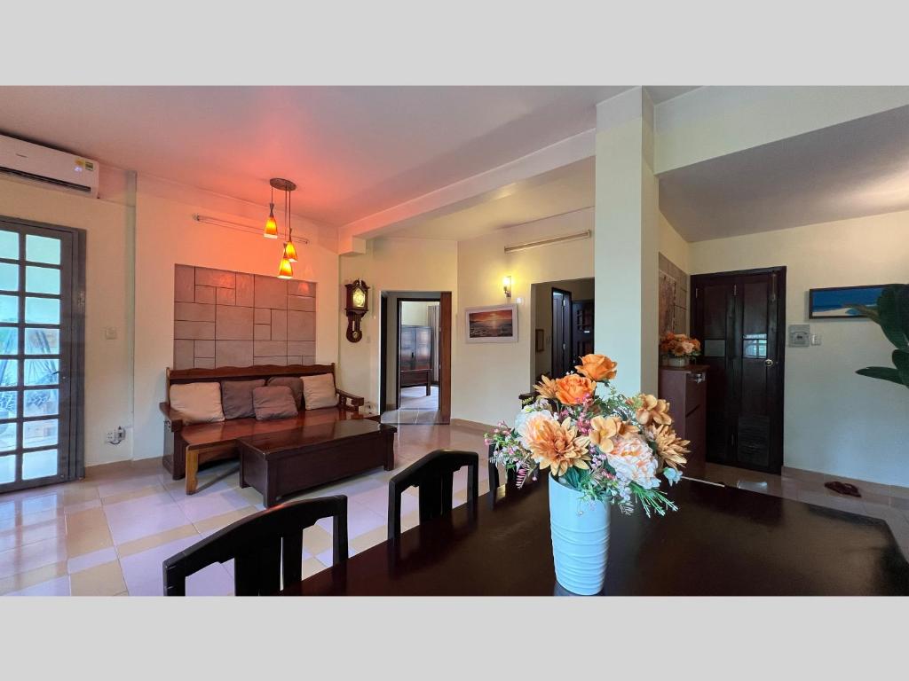 ein Wohnzimmer mit einem Tisch und einer Blumenvase in der Unterkunft Retro Saigon Loft - 990 sq ft, heart of D1 in Ho-Chi-Minh-Stadt