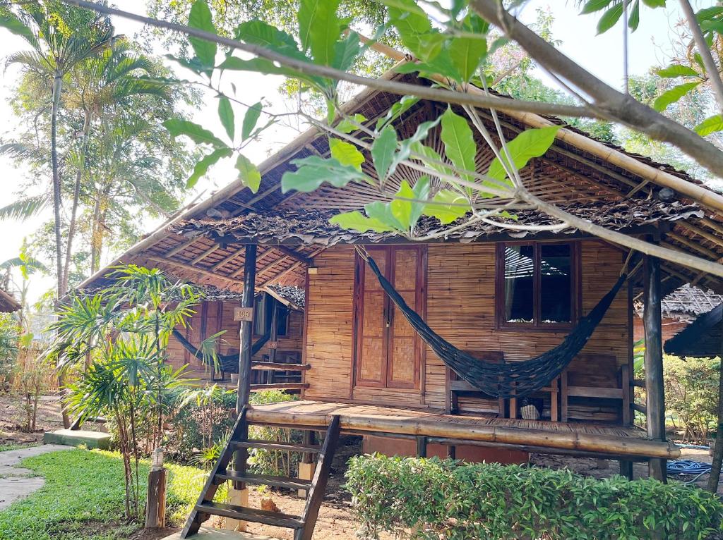 a hammock in front of a wooden house at Pai Country Hut in Pai