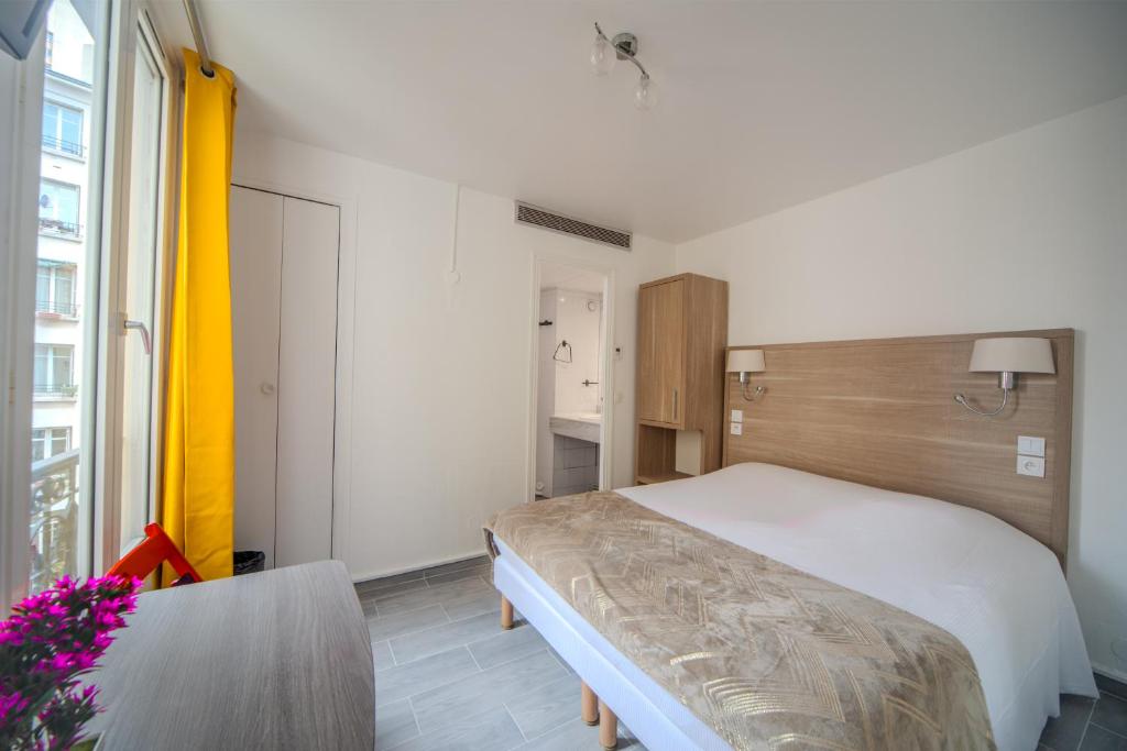 - une chambre avec un lit et une table fleurie dans l'établissement Casa Serena Paris Hôtel, à Paris