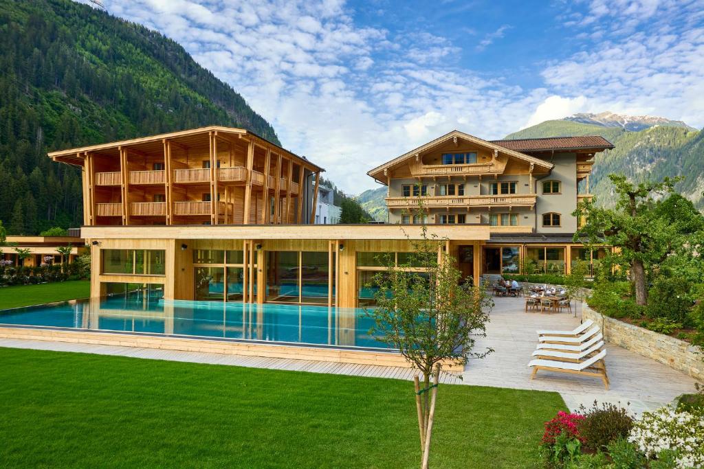 a large house with a pool in front of a mountain at Gut Stiluppe - Good Life Hotel in Mayrhofen