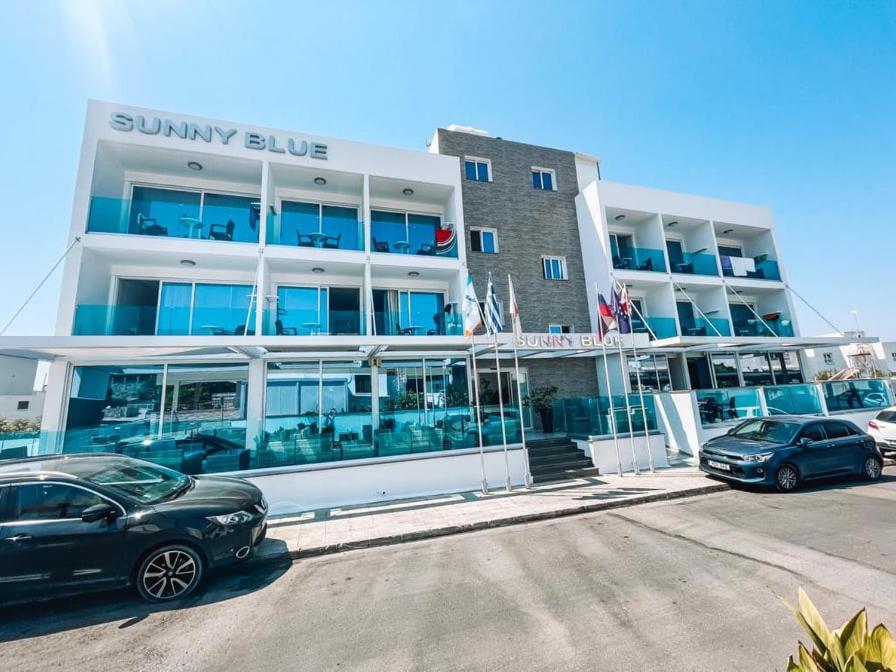 a building with cars parked in front of it at Sunny Blue Hotel in Ayia Napa