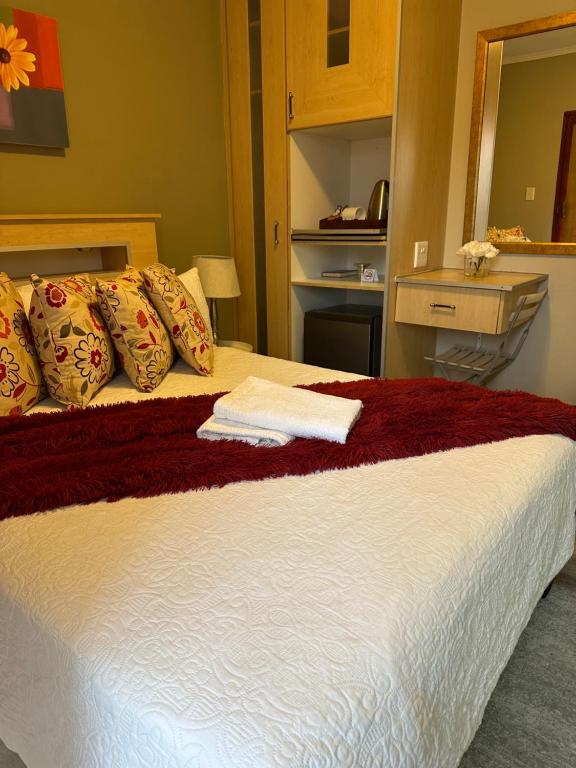 ein Bett mit einer roten und weißen Decke und einem Spiegel in der Unterkunft Repa Boutique Lodge Self-Catering Units in Kimberley