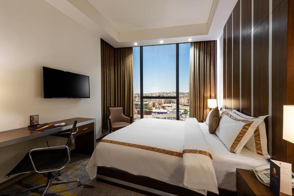 Una habitación de hotel con una cama, un escritorio y una ventana. en Sulaf Luxury Hotel, en Amán