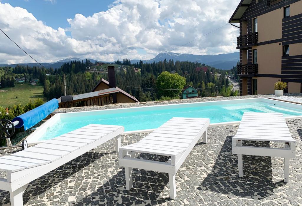 dos sillas blancas sentadas junto a una piscina en Ozone minihotel, en Yablunytsya