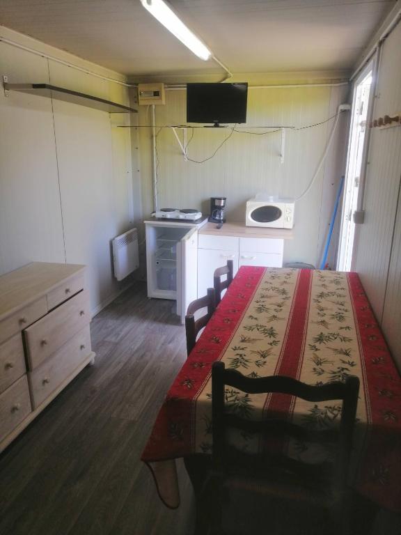 a room with a table and chairs and a kitchen at Camping à la ferme de la tournerie in Raids