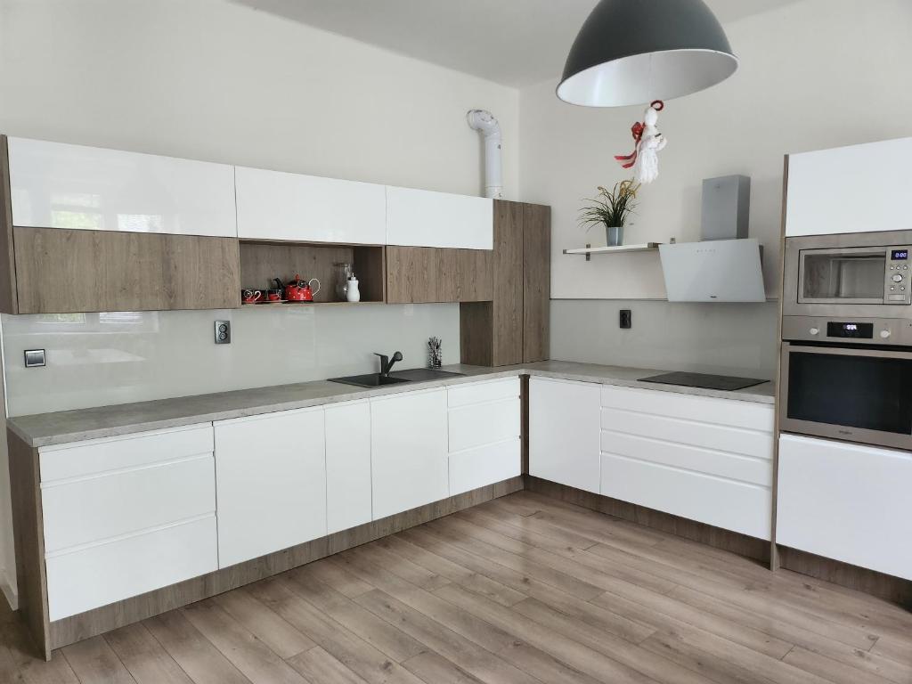 kuchnia z białymi szafkami i urządzeniami ze stali nierdzewnej w obiekcie Apartment 4kk, centrum 15m walk w mieście Moravská Ostrava