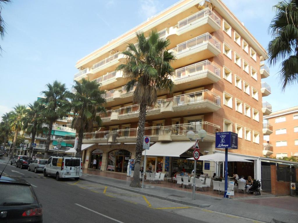 a tall building with palm trees in front of a street at Apartamentos Palas Salou in Salou