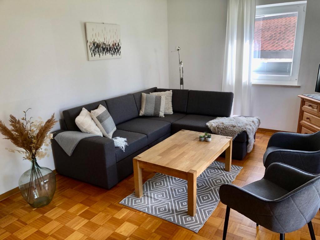 uma sala de estar com um sofá azul e uma mesa de madeira em Ferienwohnung Gartenblick em Amerang