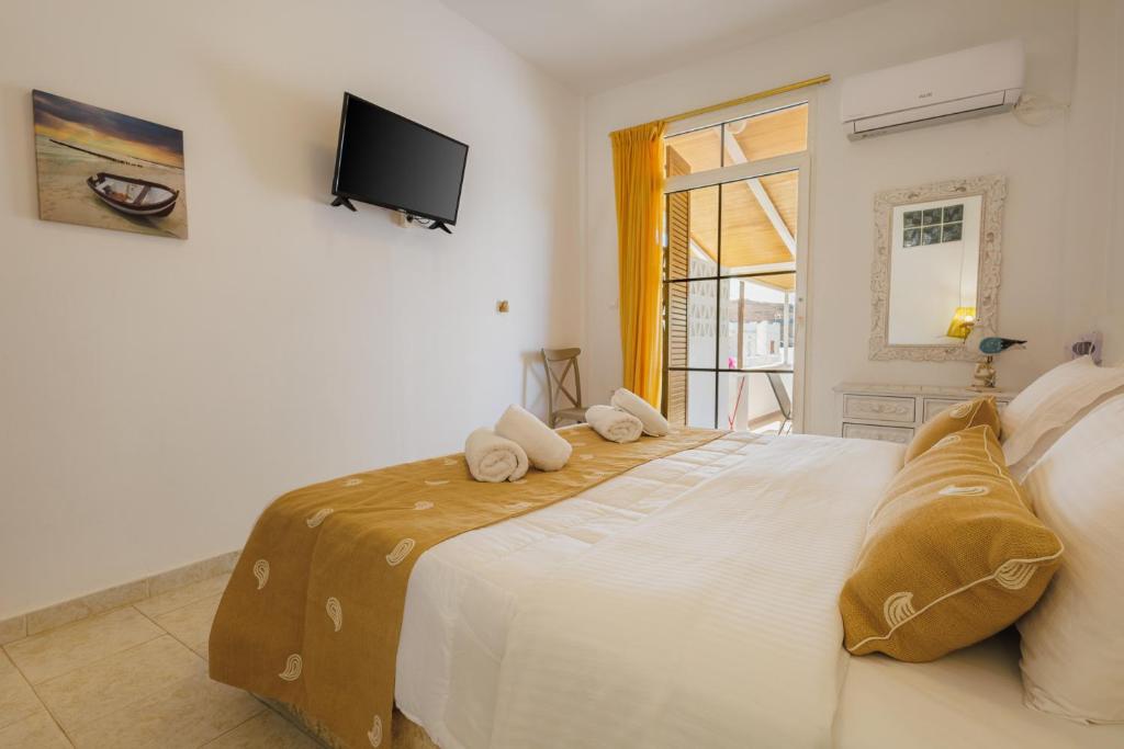 a bedroom with a large white bed with towels on it at Studios Eliza in Livadi