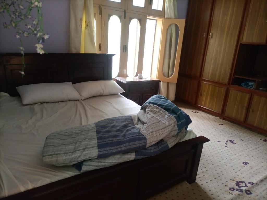 ein unmaskiertes Bett in einem Zimmer mit Fenster in der Unterkunft Bojol Guesthouse bilamike thoursay in Skardu