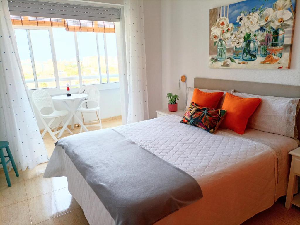 1 dormitorio con 1 cama grande con almohadas de color naranja en Apartamentos Hondahouse en Playa Honda Mar Menor, 1 o 2 dormitorios, en Playa Honda