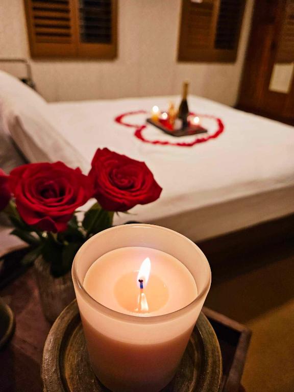 a candle sitting on a table next to red roses at The Gamekeepers Spa Cottage in Tamborine Mountain in Mount Tamborine