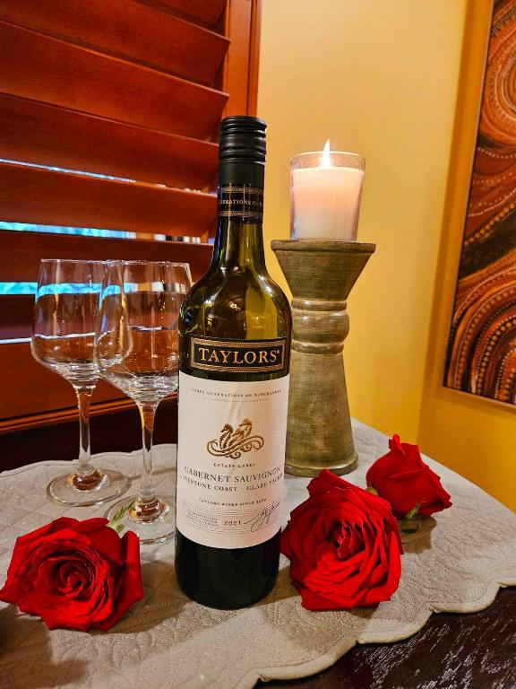 a bottle of wine sitting on a table with two glasses at The Gamekeepers Spa Cottage in Tamborine Mountain in Mount Tamborine