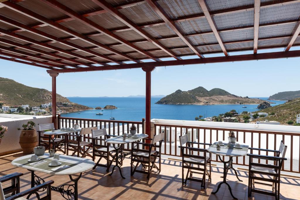 a balcony with tables and chairs and a view of the ocean at Golden Sun Hotel Patmos in Patmos